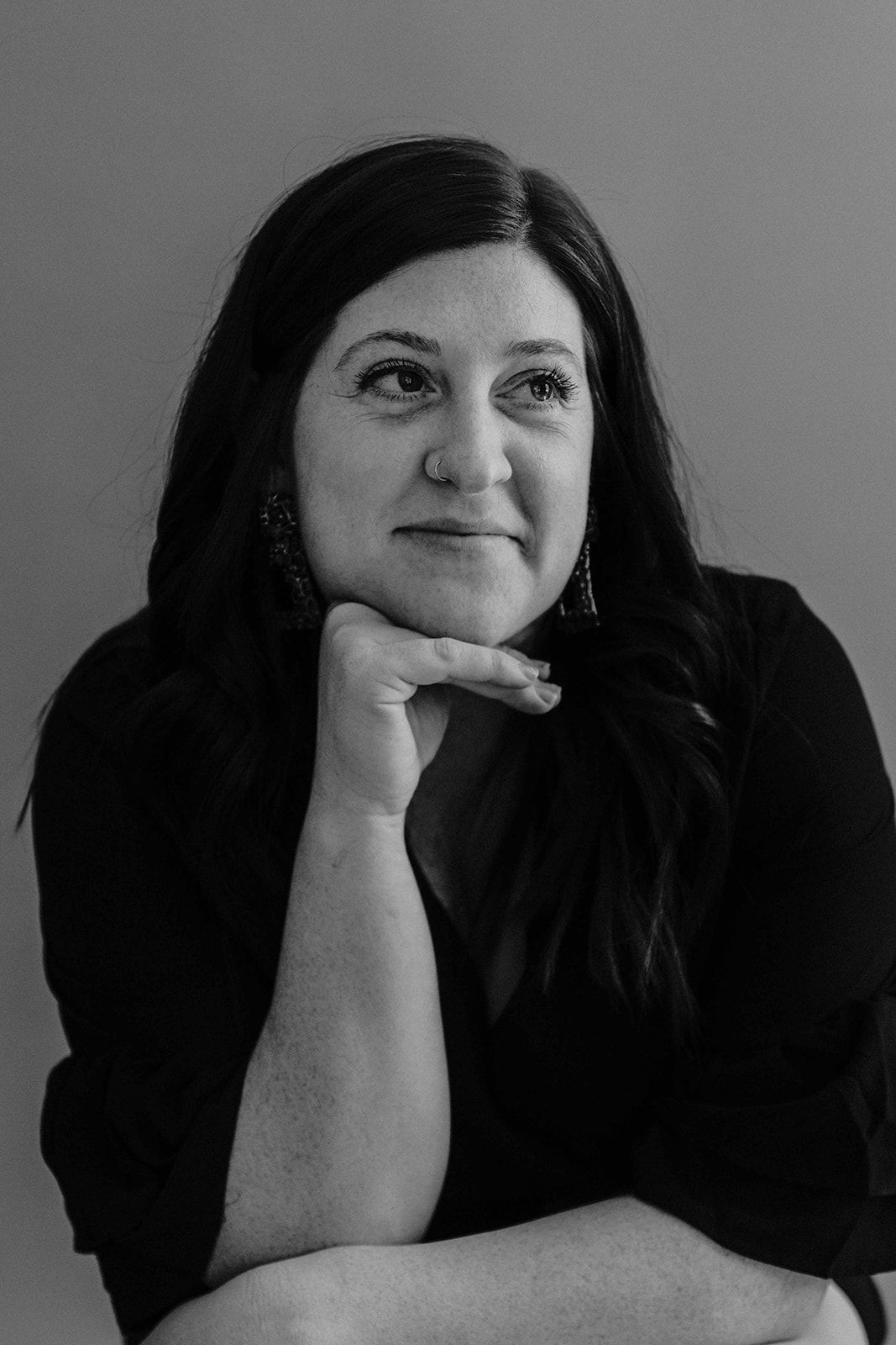 Black and white headshot of founder, Emilee Friedman Fechter, with chin resting on hand and looking off camera.